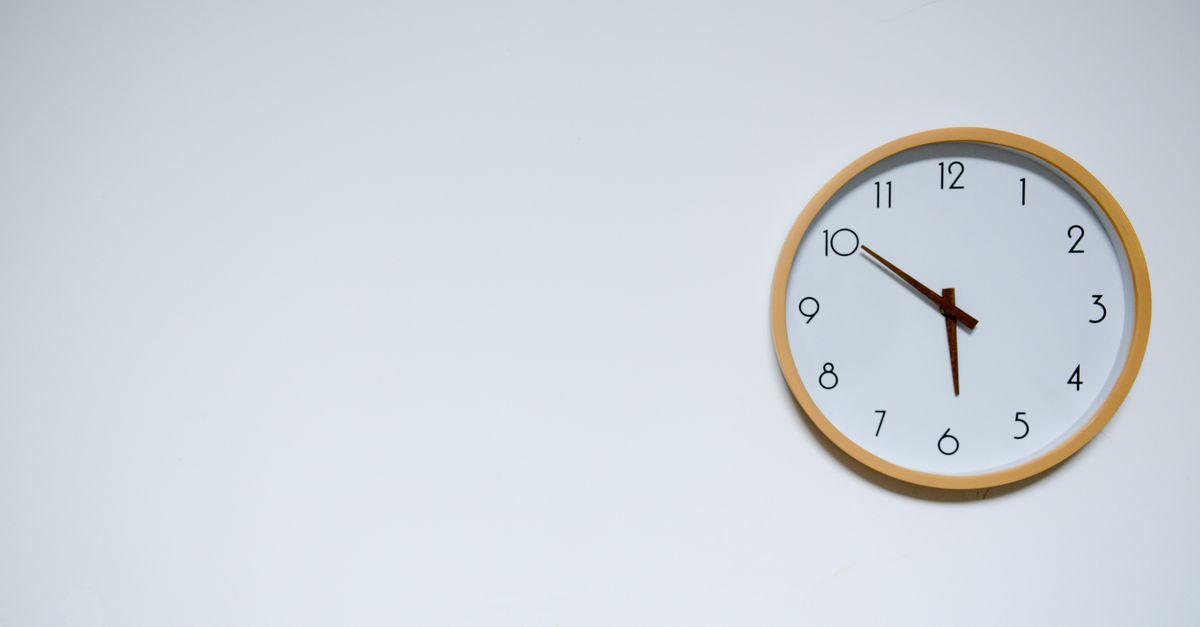Simple wall clock with wooden frame against a white background, showing the time 10:10.